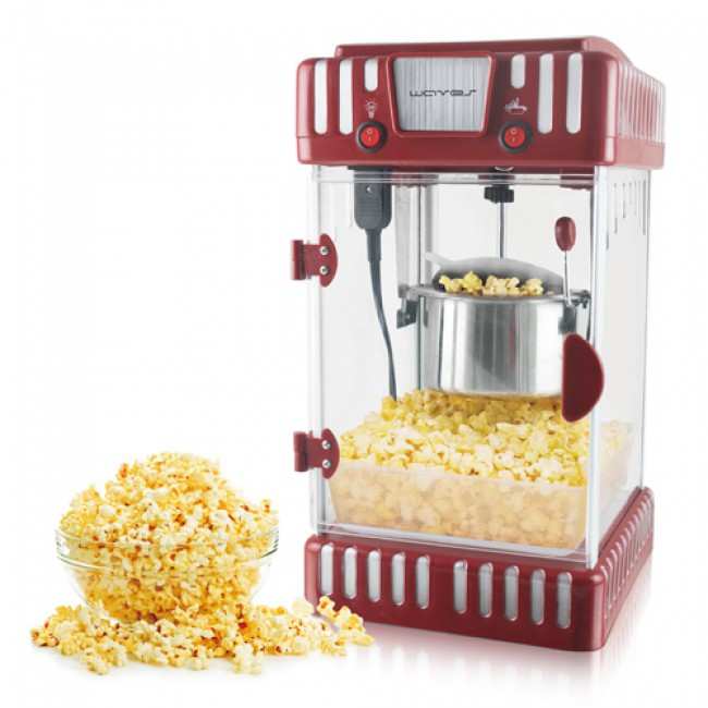 Mindre men effektiv och mycket populär popcornmaskin med gryta för 0,5 dl opoppade popcornkärnor, popcornmaskinen är genomskinlig med röda detaljer och popcorn i dess tråg samt i skål som står bredvid.